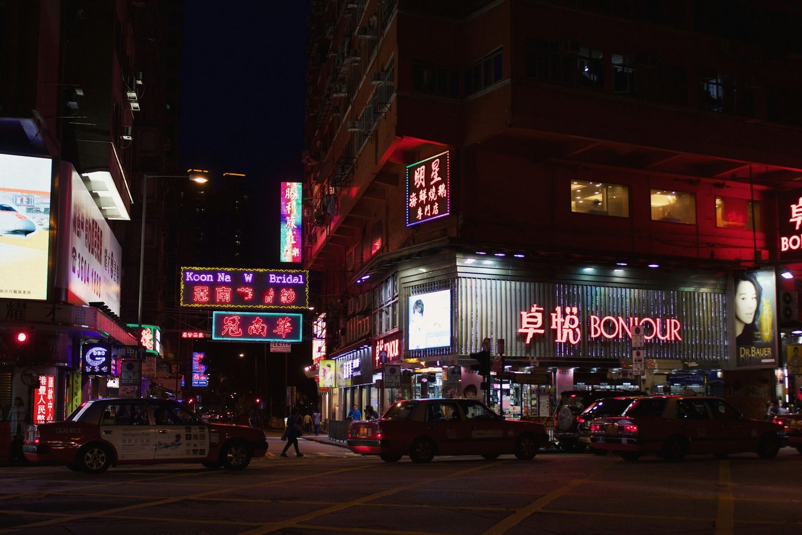 vehicles on road with people walking near buildings during nighttime